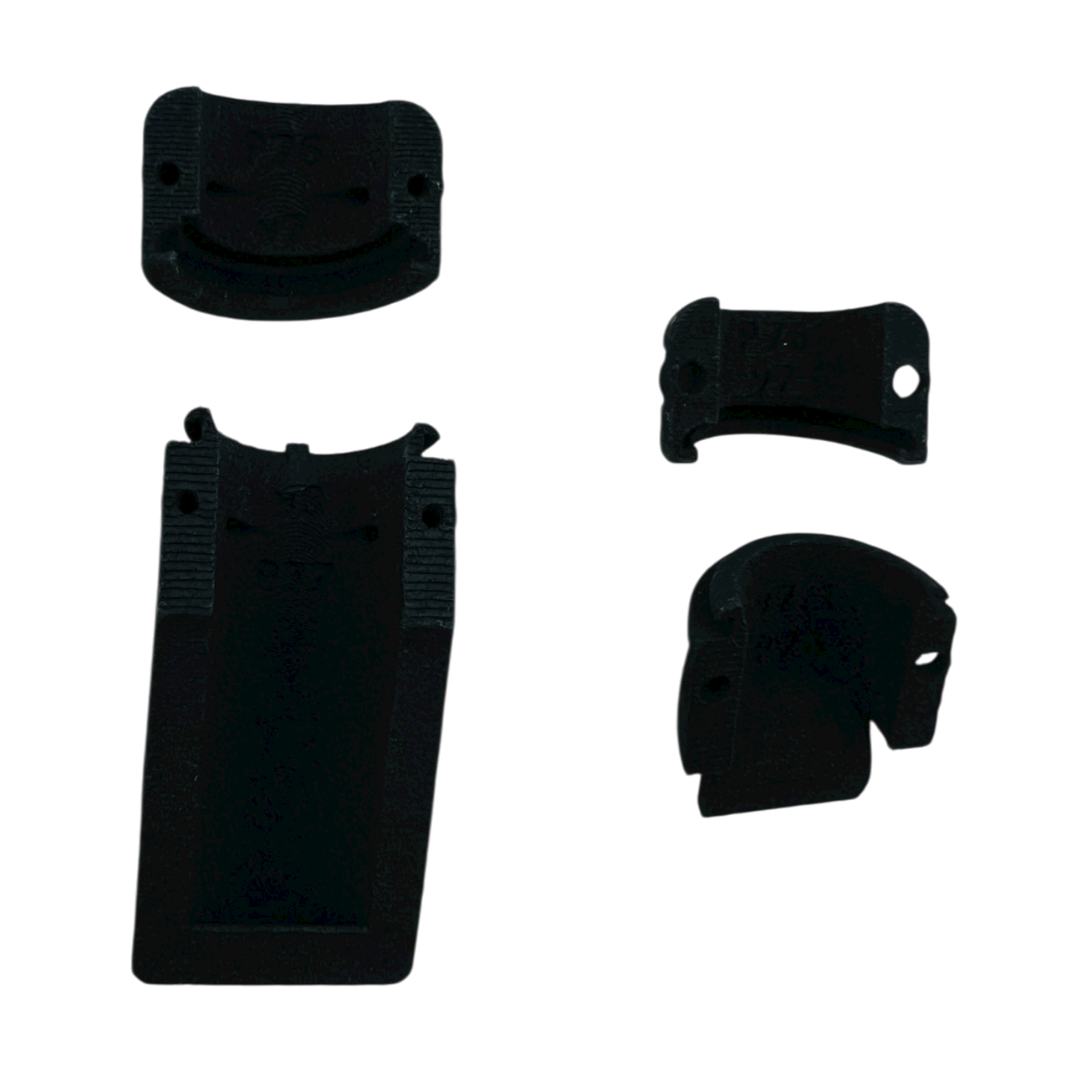 Four black plastic components of varying shapes, likely parts for an assembly or tool.